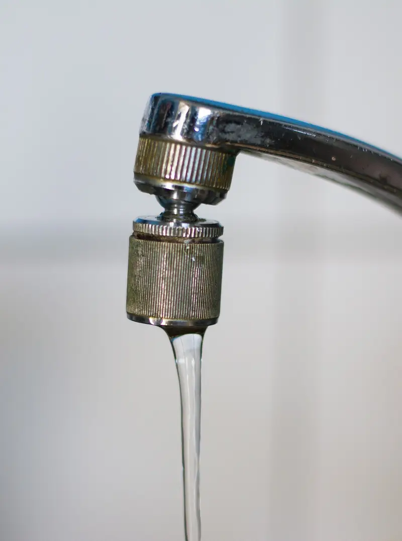 Close-up of an old chrome tap with a thin stream of water running from it